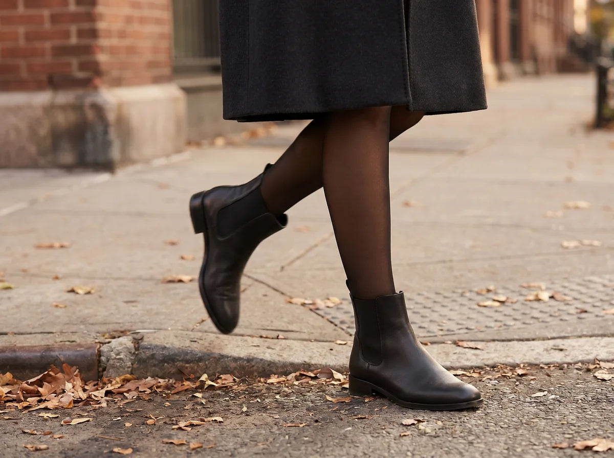 A woman in sheer black Willa tights mid-stride on a winter city sidewalk